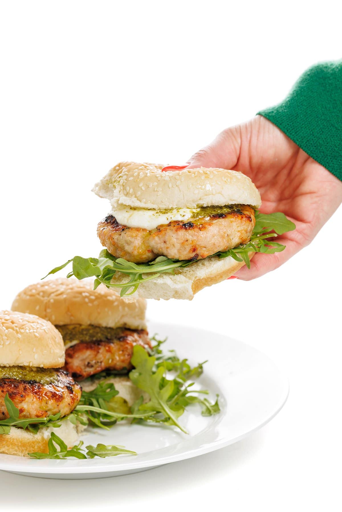 Holding a grilled turkey burger with pesto.