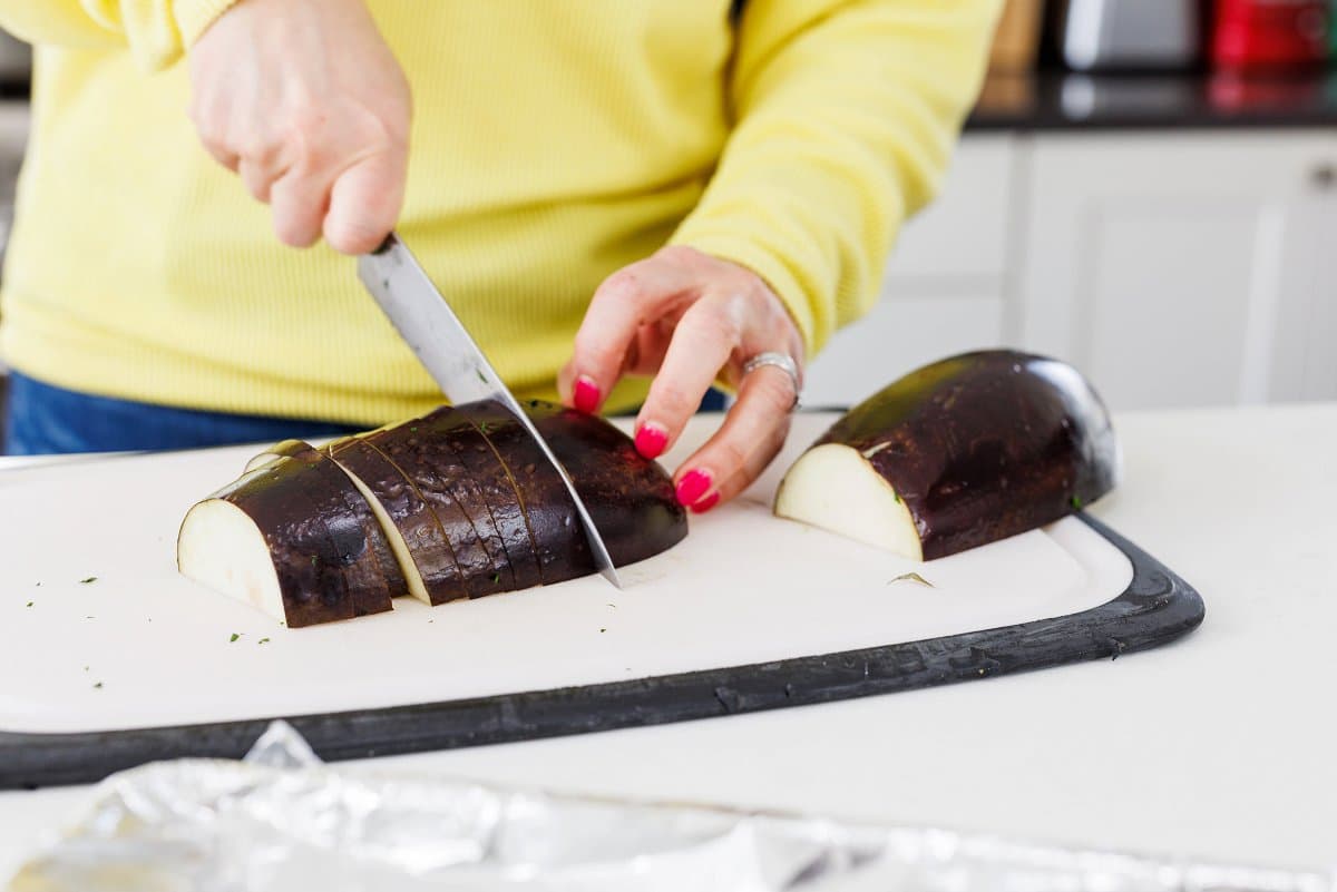 Liz cutting an eggplant on a cutting board.