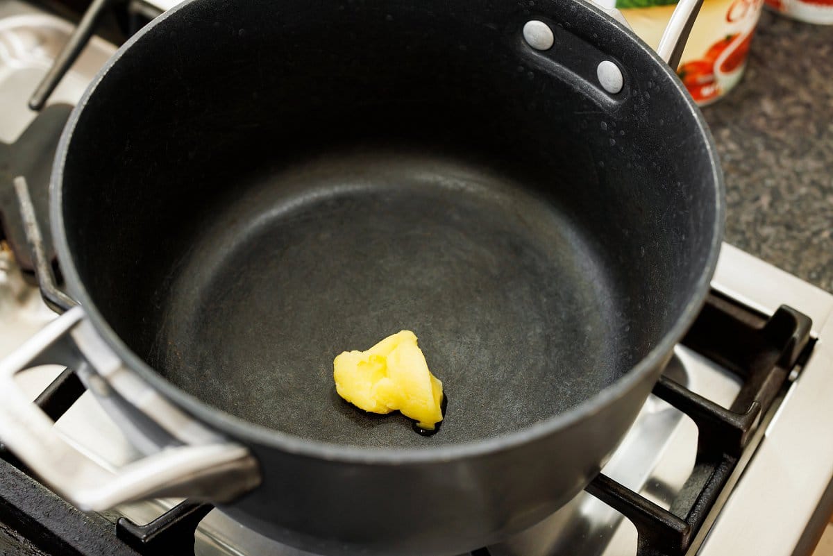 Melting ghee in the bottom of a large pot.