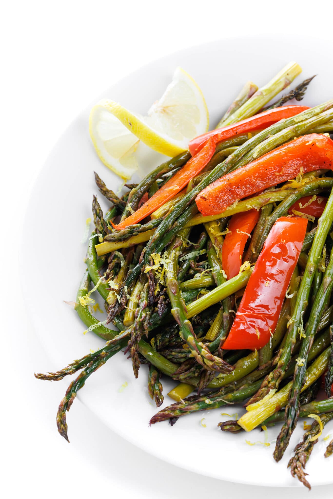Roasted Asparagus with Red Peppers on a plate with a lemon slice.