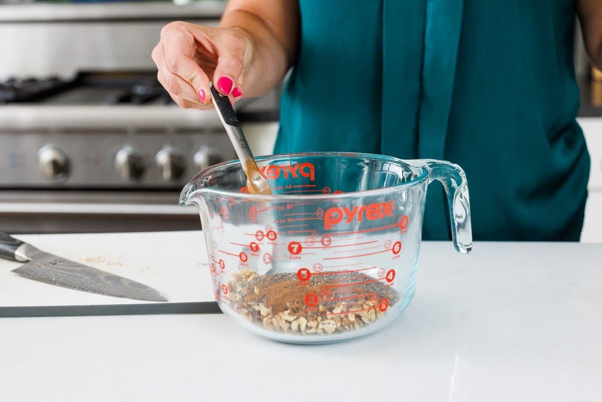 Pouring warm spices in with seeds and nuts.