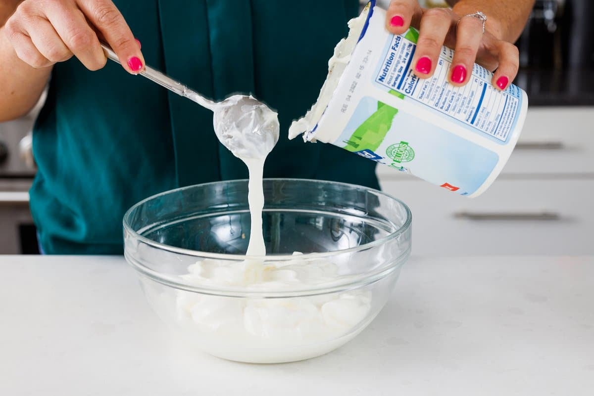 Pouring yogurt into large glass bowl.
