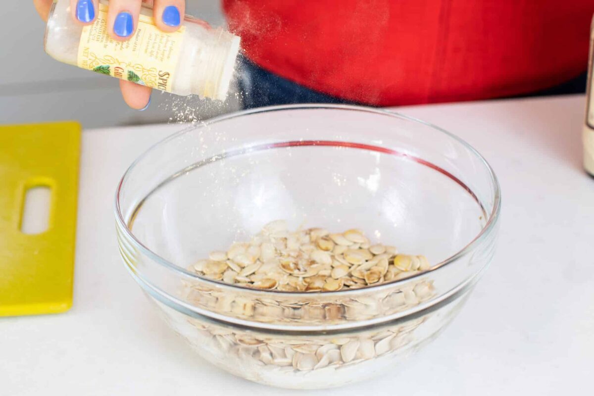Sprinkling seasonings on pumpkin seeds.