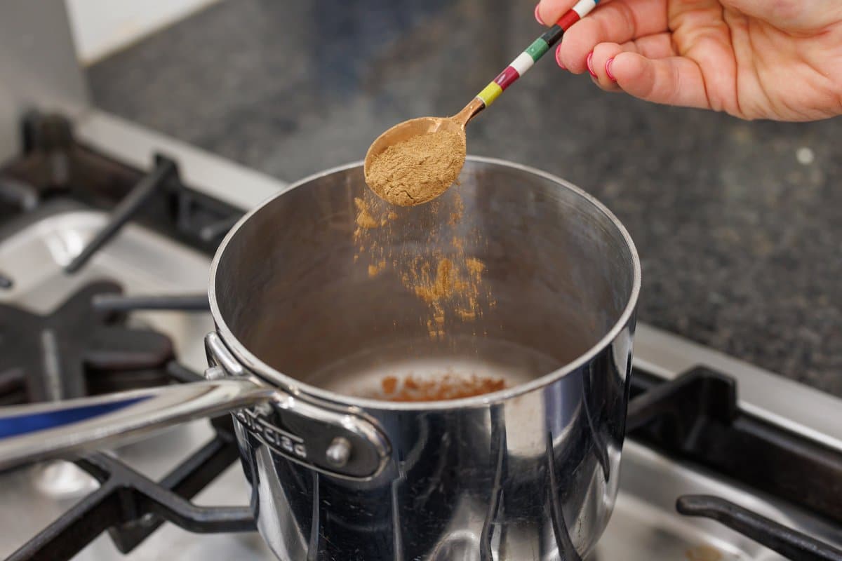 Adding cinnamon to saucepan.