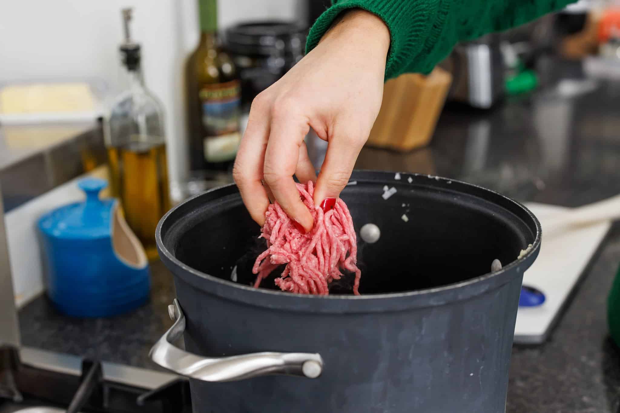 Adding ground lamb to large soup pot.