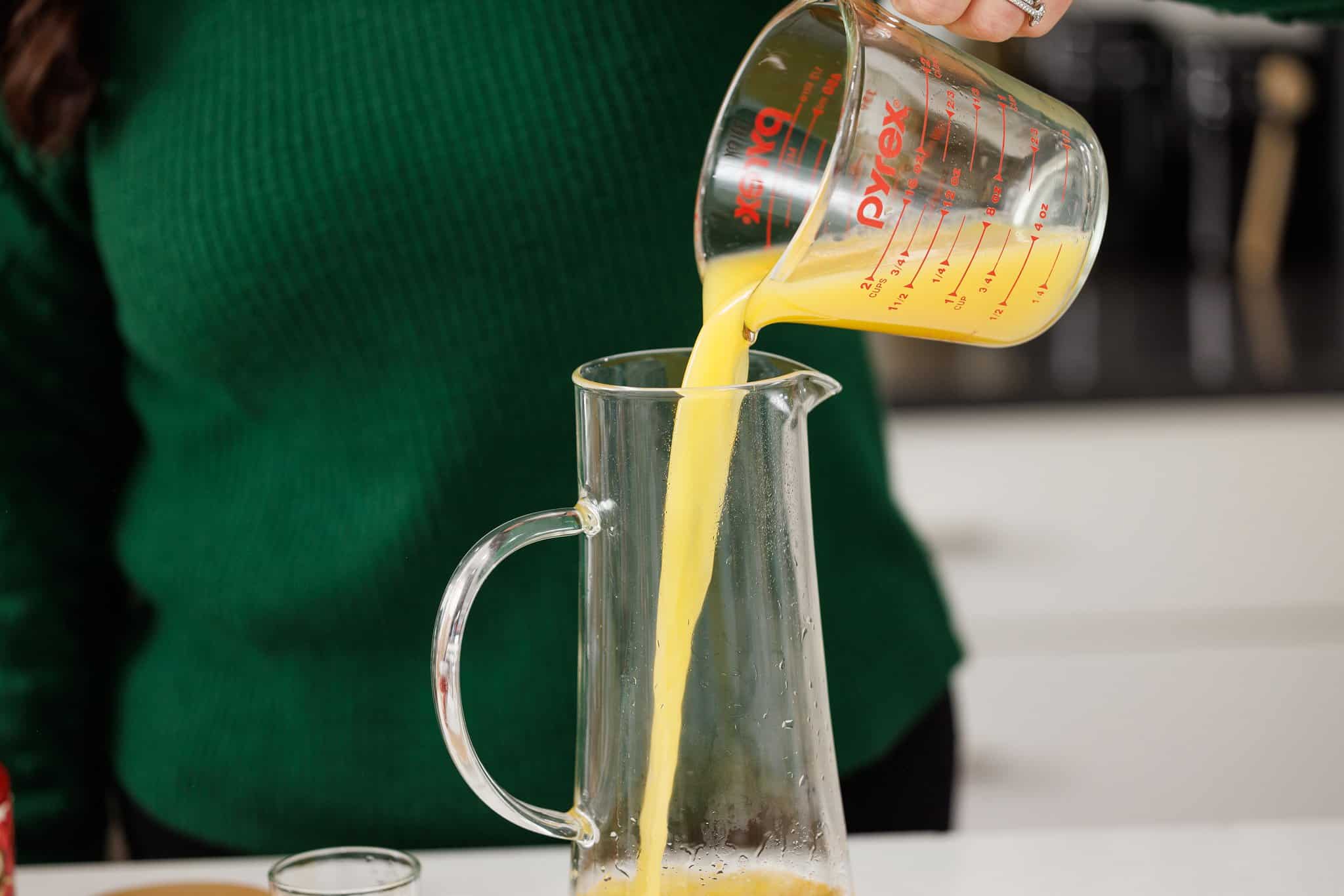 Pouring orange juice into pitcher.