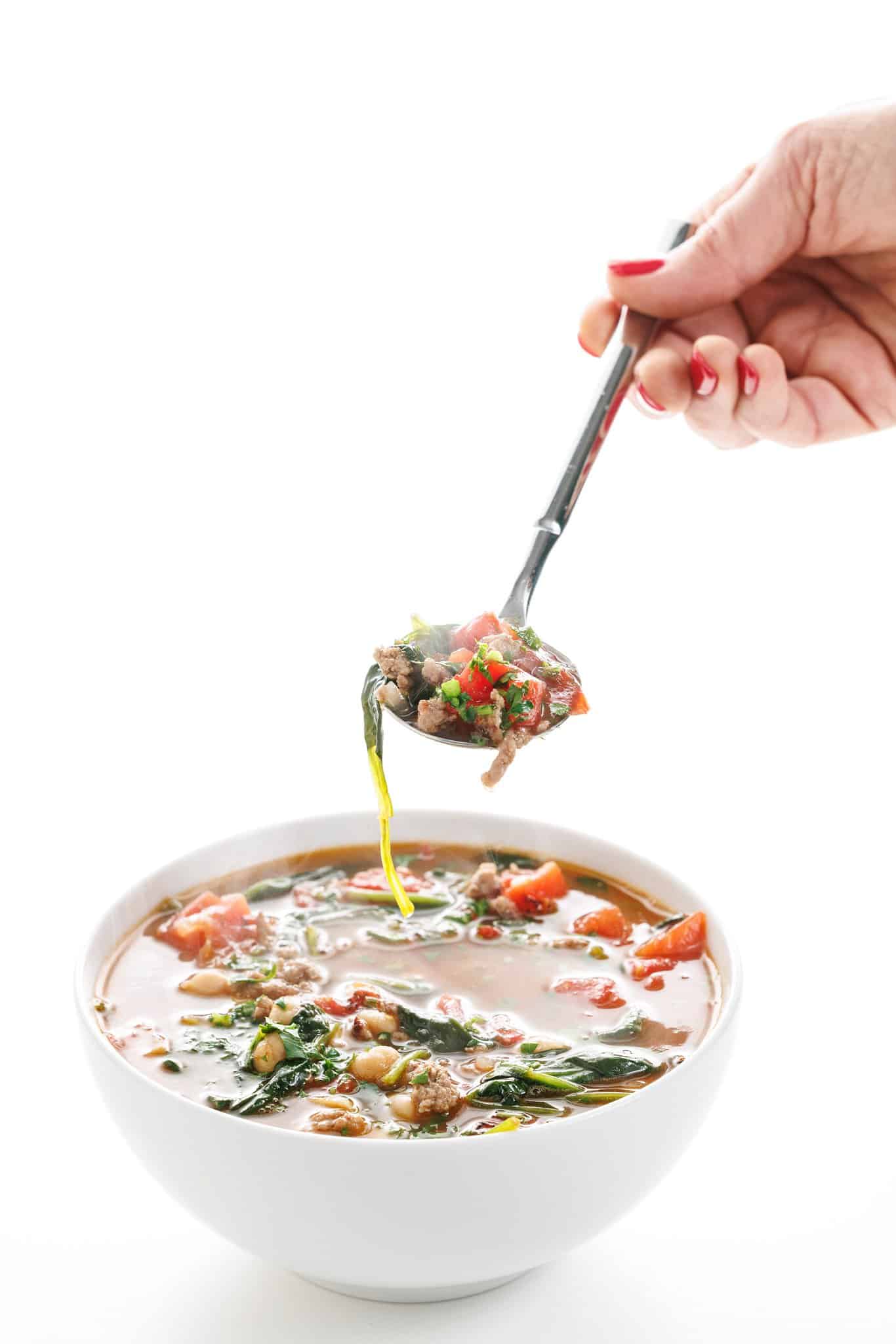 Spoonful of lamb & chickpea stew with spinach over a white bowl of soup.