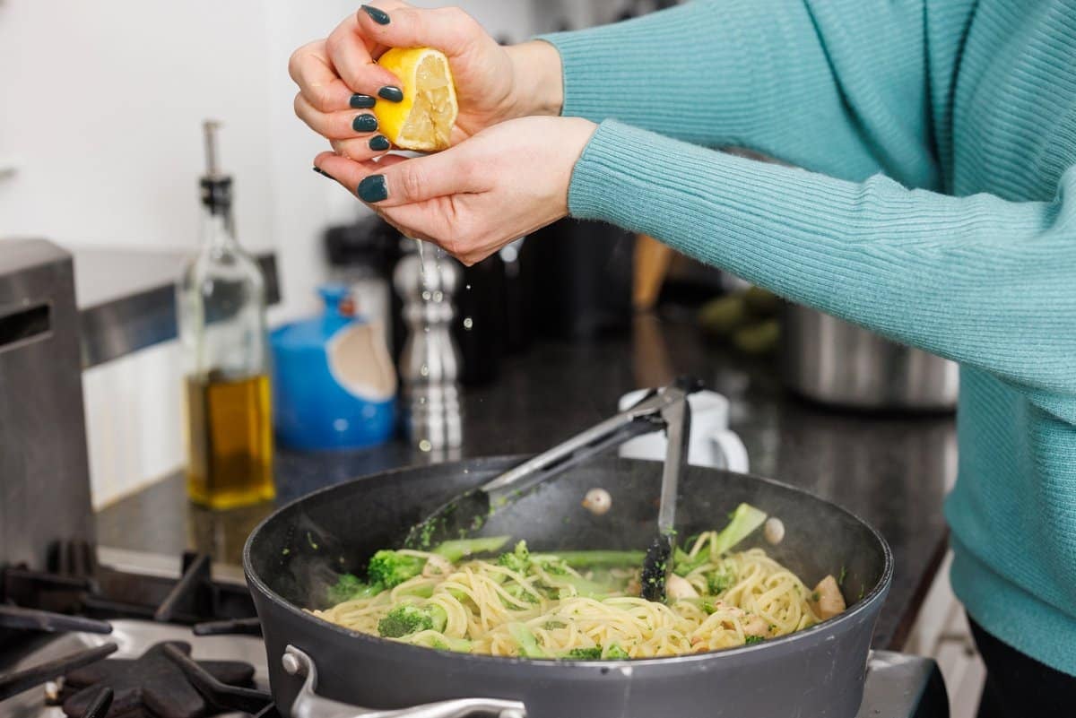 Lemon squeezing fresh lemon juice over pasta.