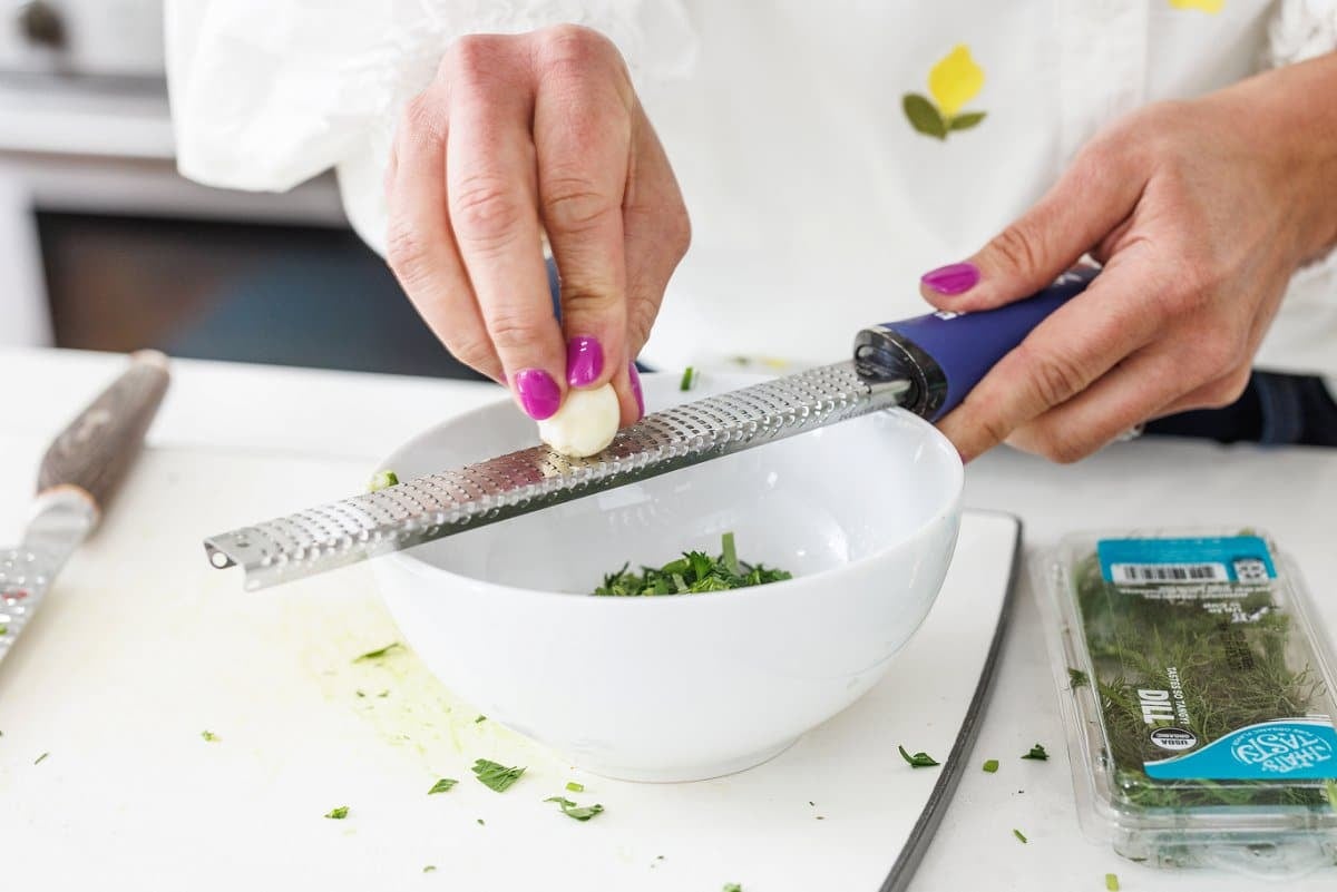 Grating garlic with a microplane into a bowl.