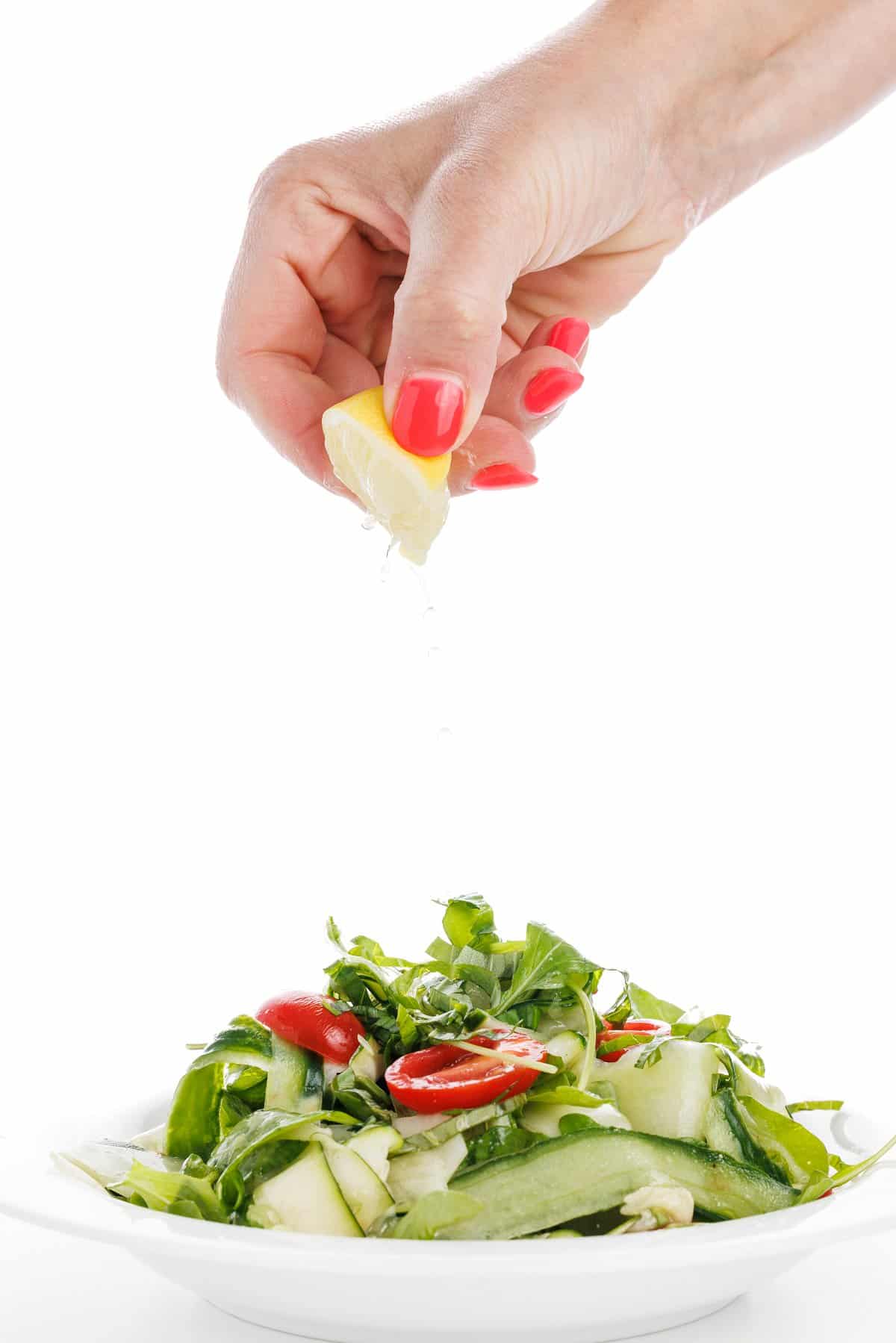 Garnishing cucumber zucchini salad with fresh lemon juice.