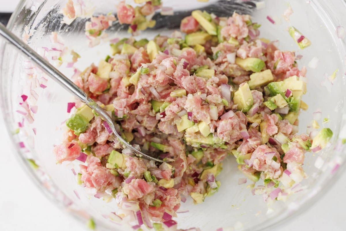 Stirring ahi tuna ceviche together in bowl.