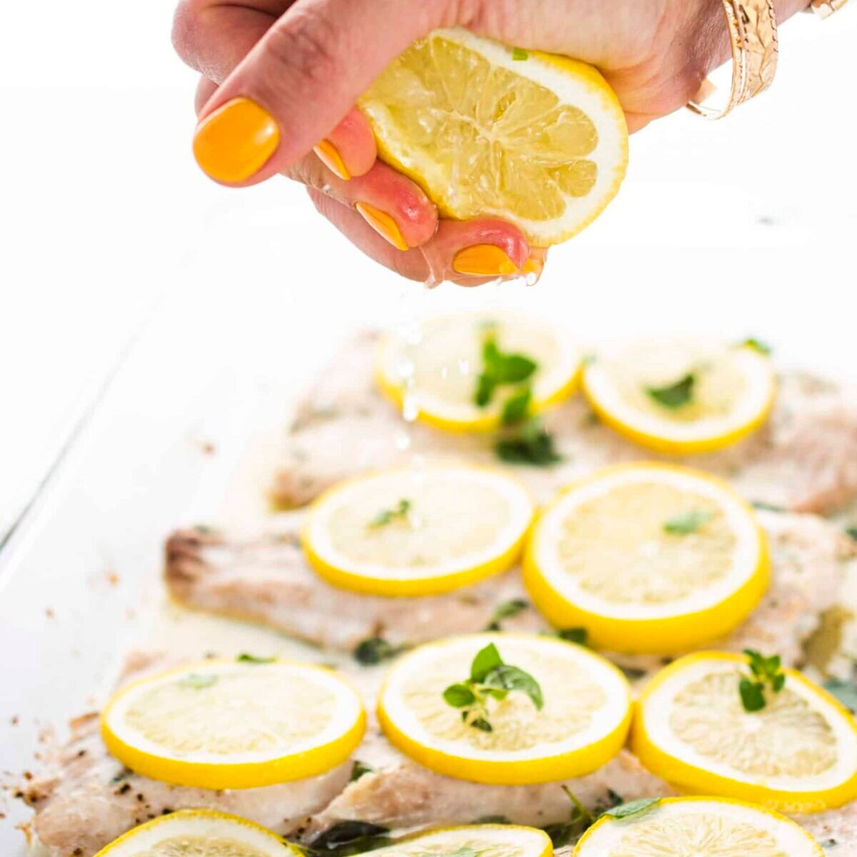 Garnishing baked white fish with fresh lemon juice, 1 of 15 healthy baked fish recipes.
