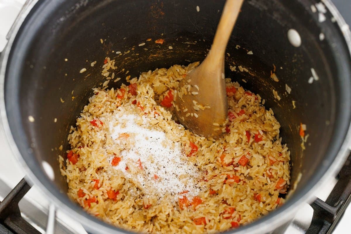 Stirring rice with onion and bell pepper and seasonings.
