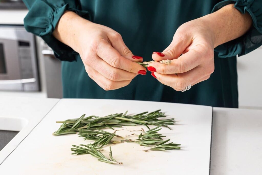 Liz take rosemary and breaking it into smaller sprigs.