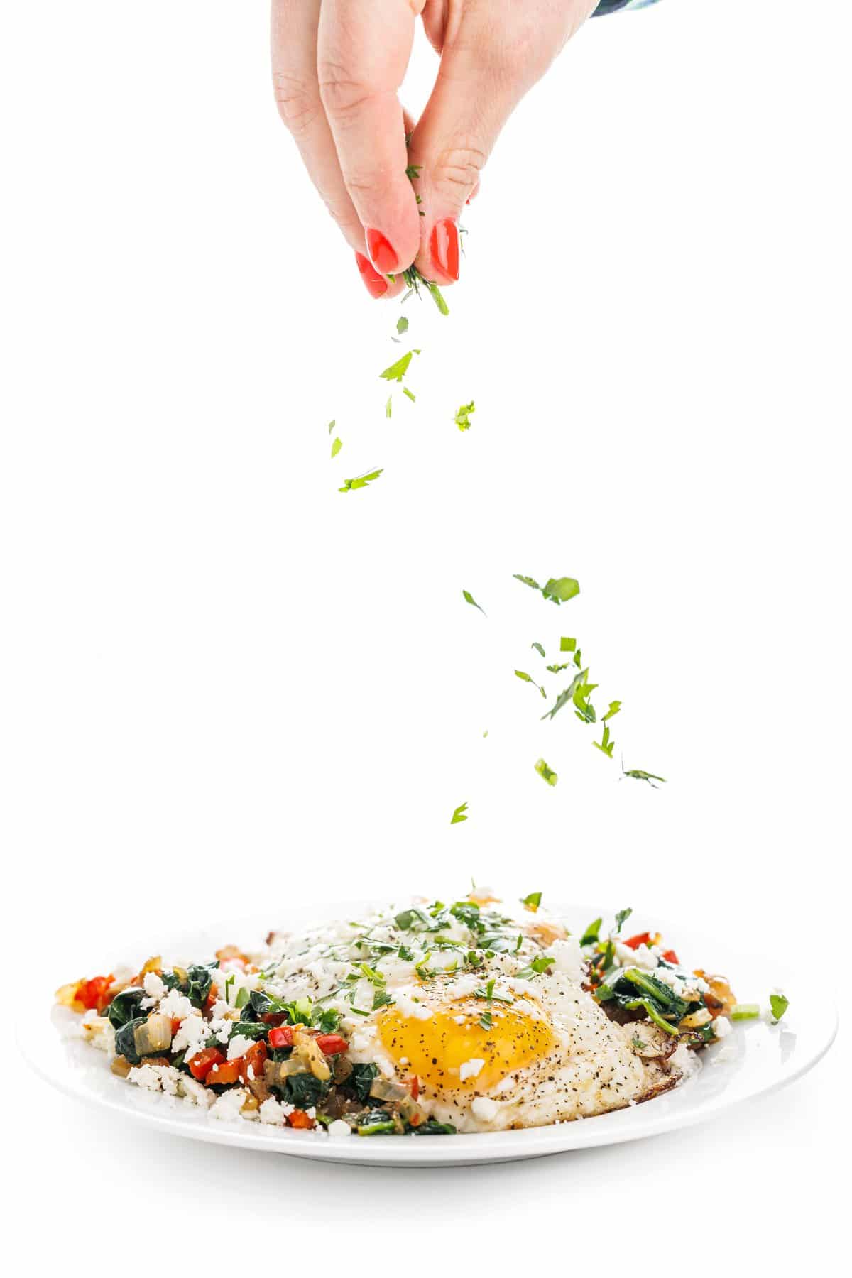 Garnishing Greek breakfast egg skillet with parsley.