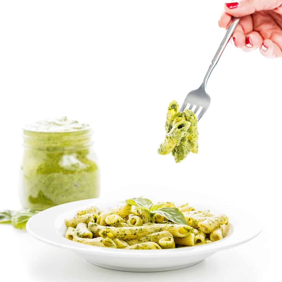 a hand holding a fork over a plate of pasta