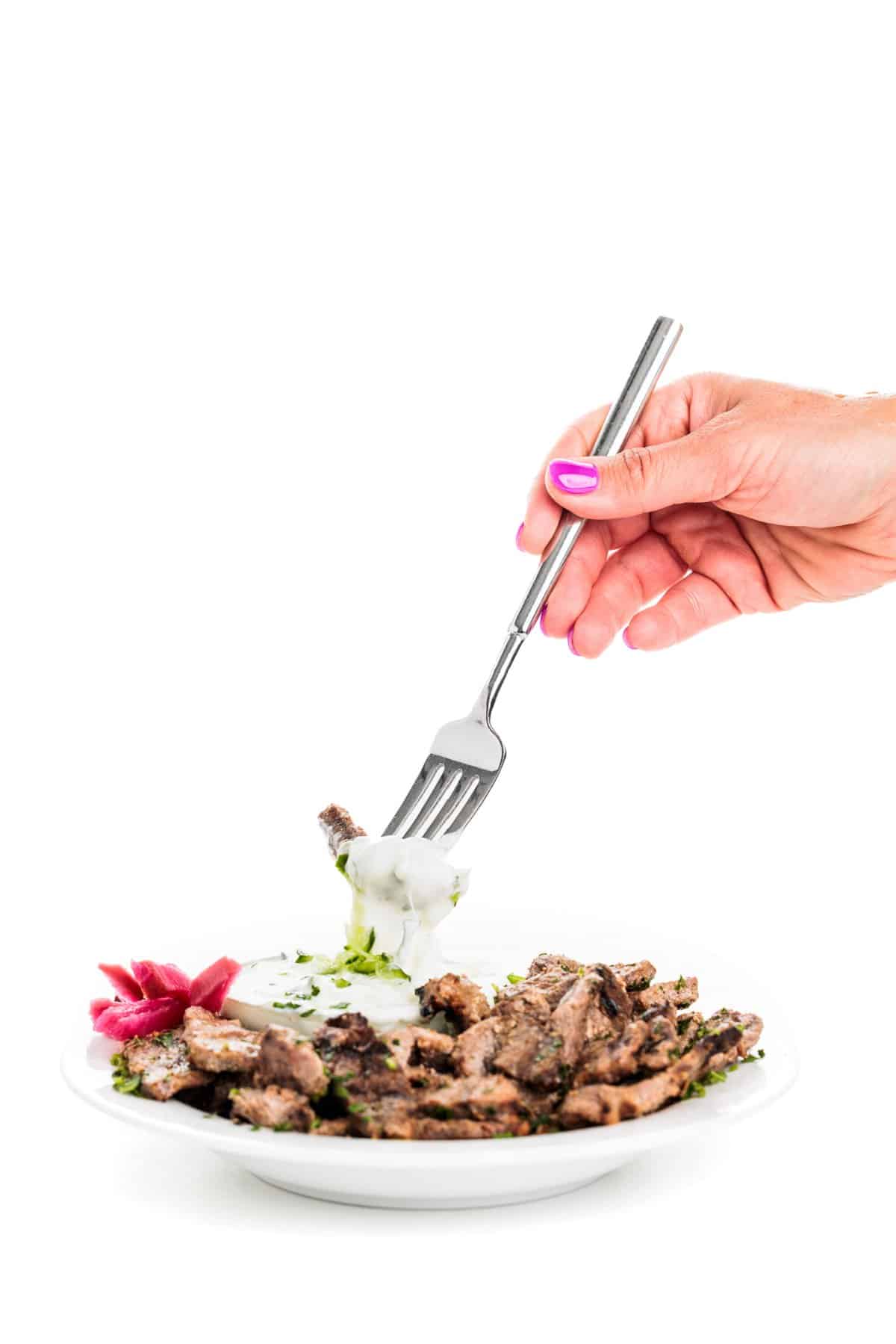 Forkful of beef shawarma with cucumber yogurt sauce.