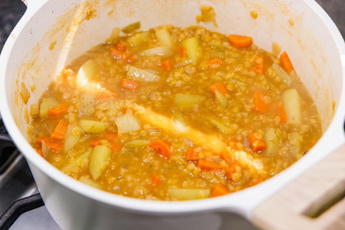 Chicken broth added to lentils and veggies in a pot.