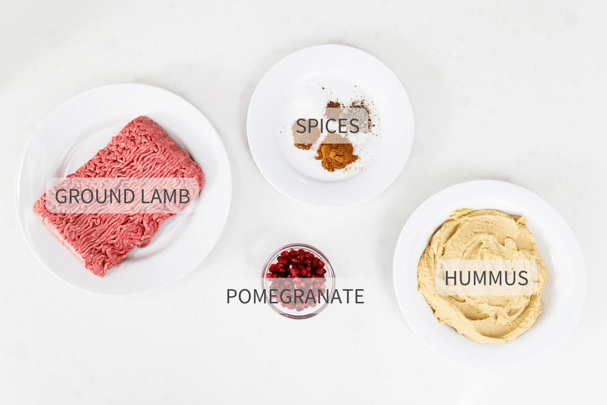 Labeled ingredients for warm hummus with ground lamb and pomegranate on white dishes.