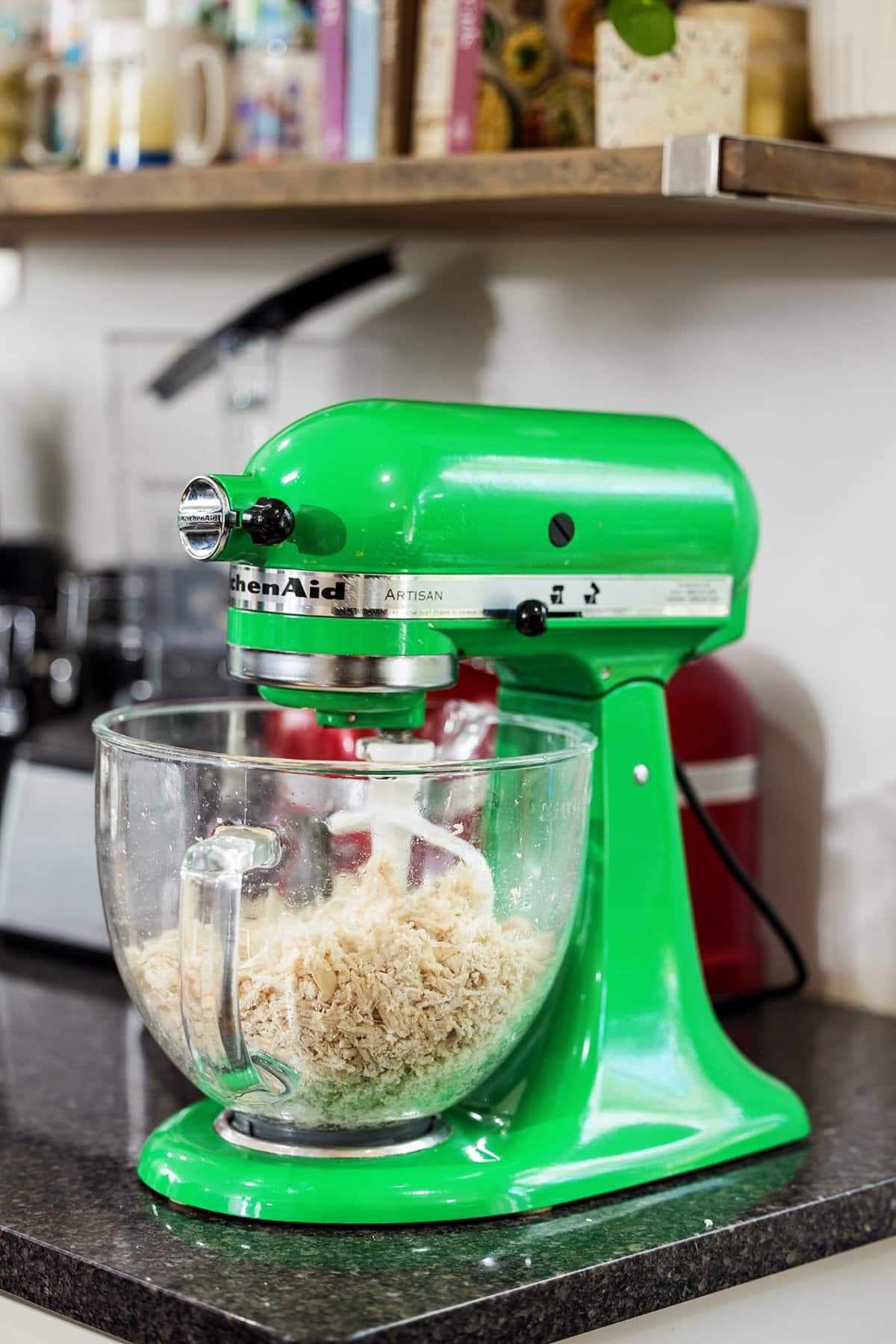 Shredding chicken in a green standing mixer.