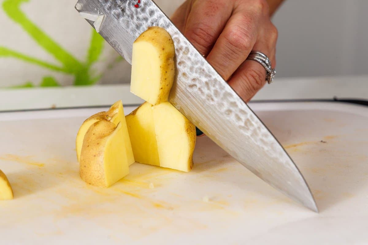 Cutting Yukon gold potatoes into chunks.