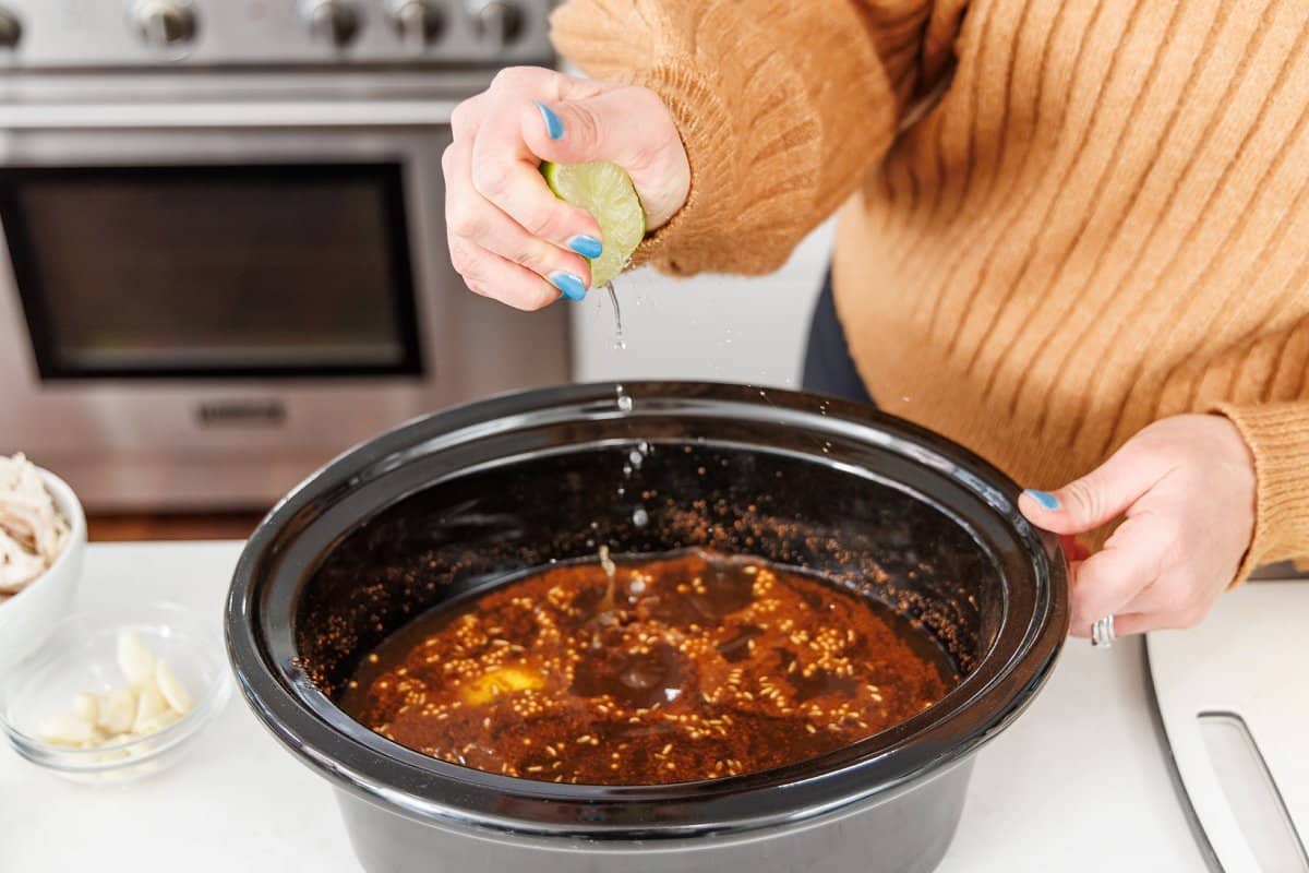 Squeezing fresh lime juice into soup in a slow cooker.