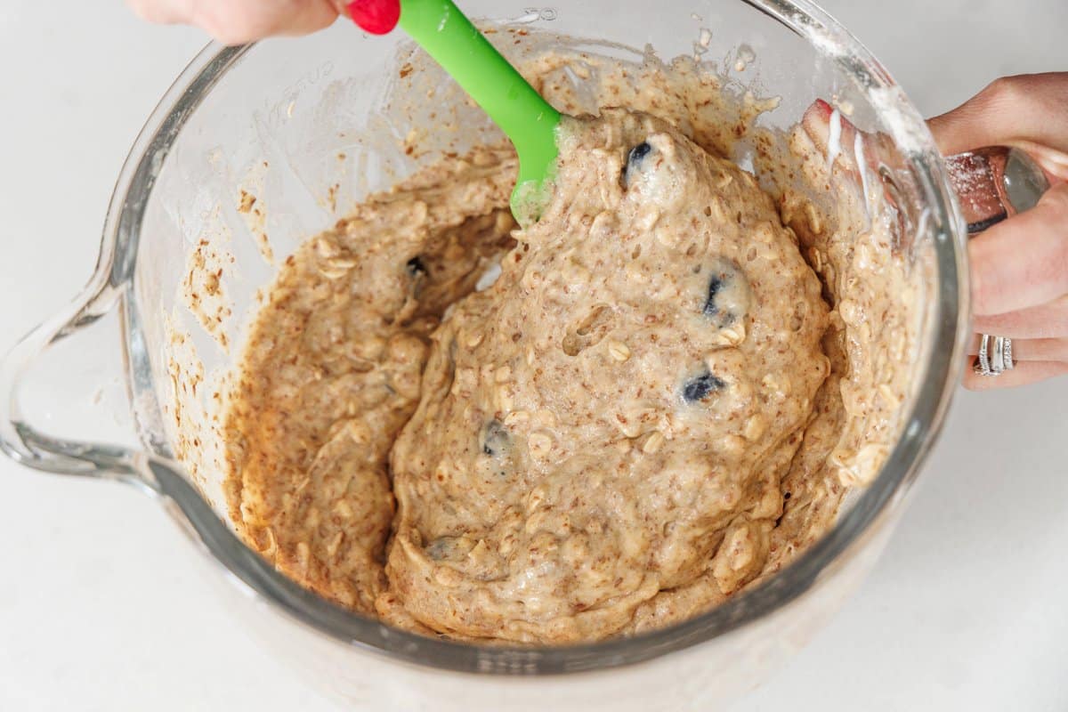 Folding fresh blueberries into bread batter with a rubber spatula.
