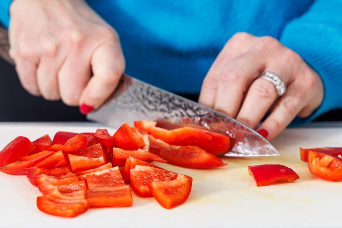 Liz cutting a red bell pepper into squares.