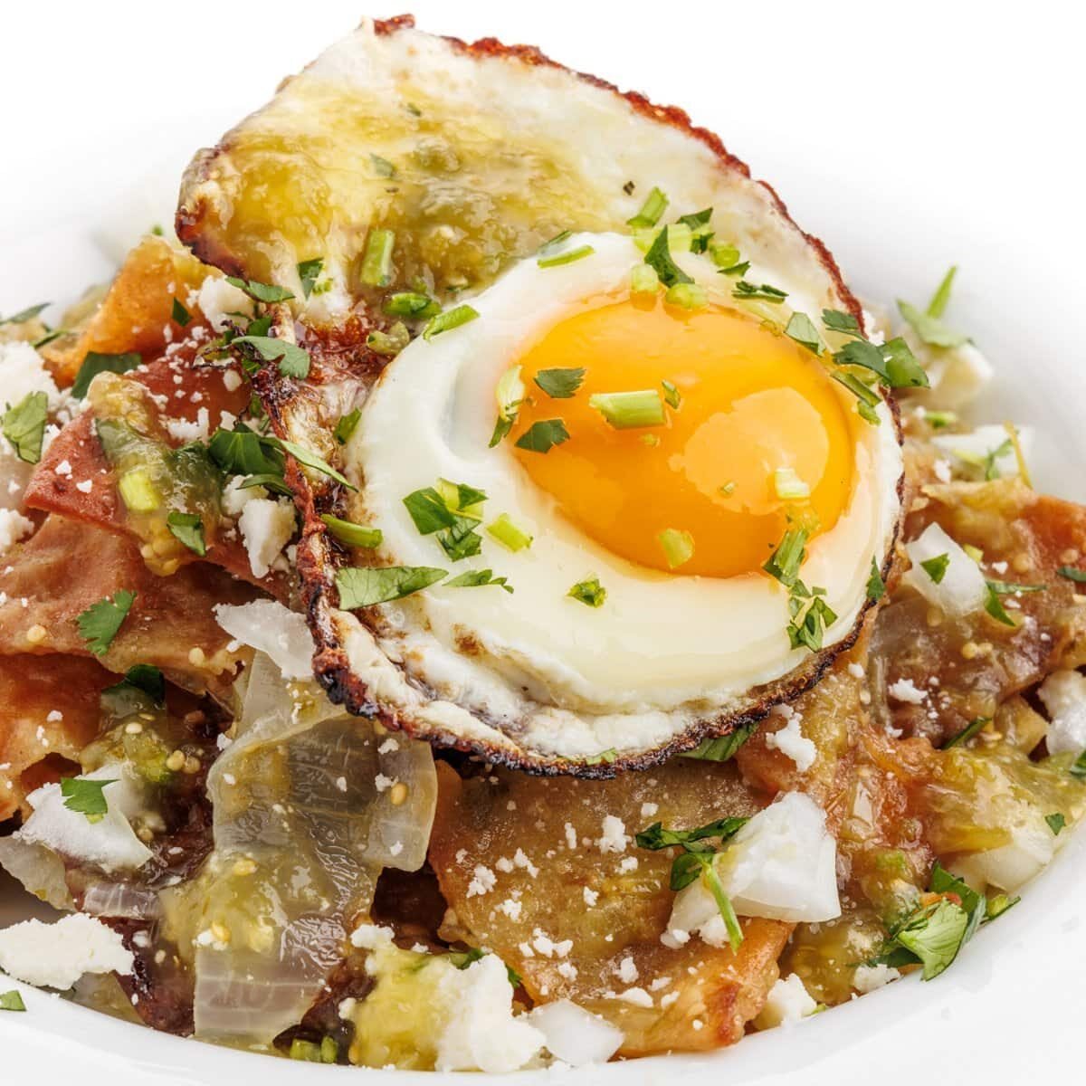 Chilaquiles verdes with a fried egg, fresh cilantro, and queso fresco.