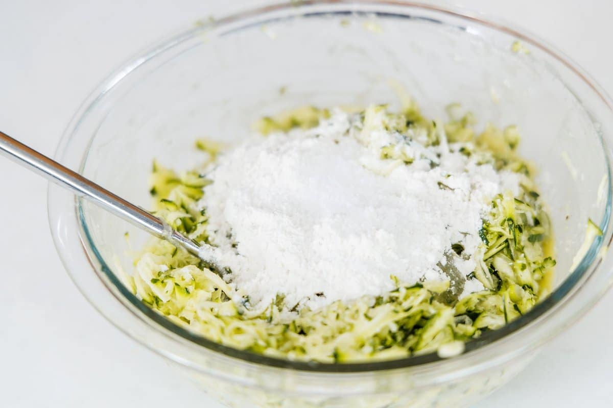 Flour added to bowl of grated zucchini and scallions.