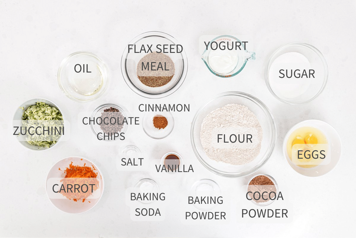 Labeled ingredients for chocolate zucchini carrot bread on a white backdrop.