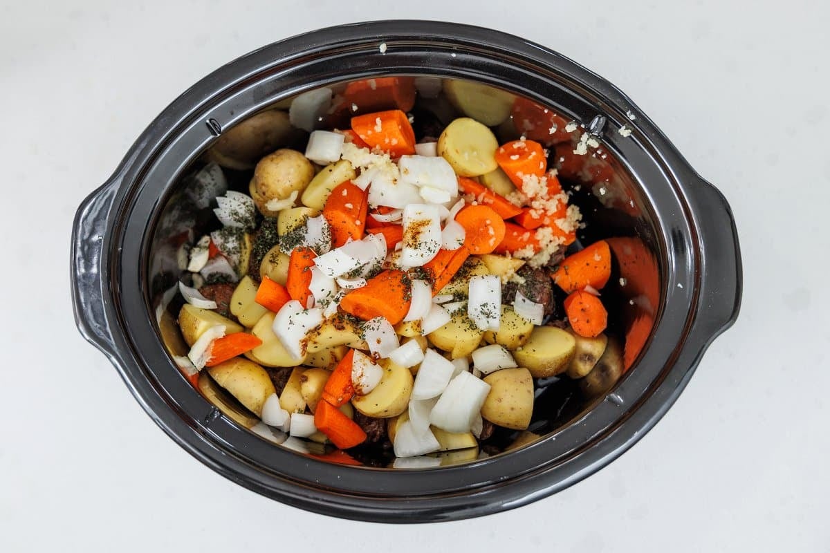 Ingredients for Irish beef stew in a slow cooker bowl.