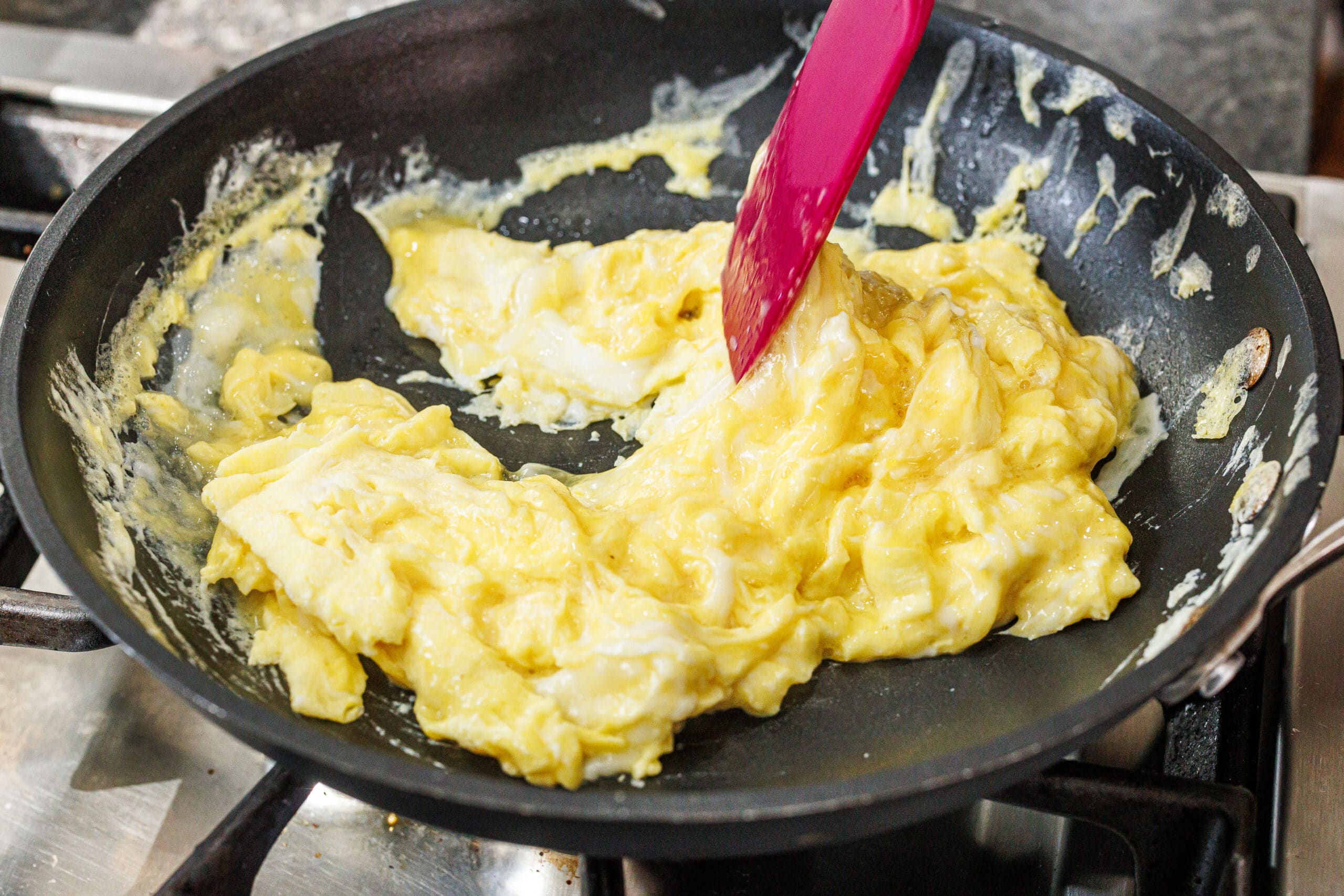 Cooking scrambled eggs in a skillet on the stove.