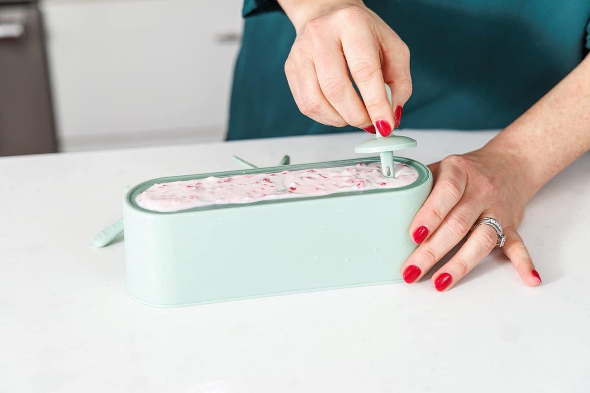 Pouring raspberry yogurt mixture into popsicle mold.