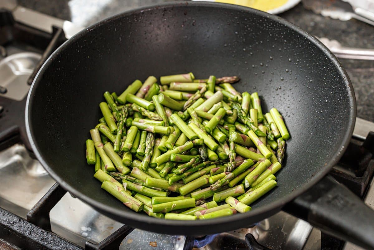 Cooking chopped asparagus in wok.