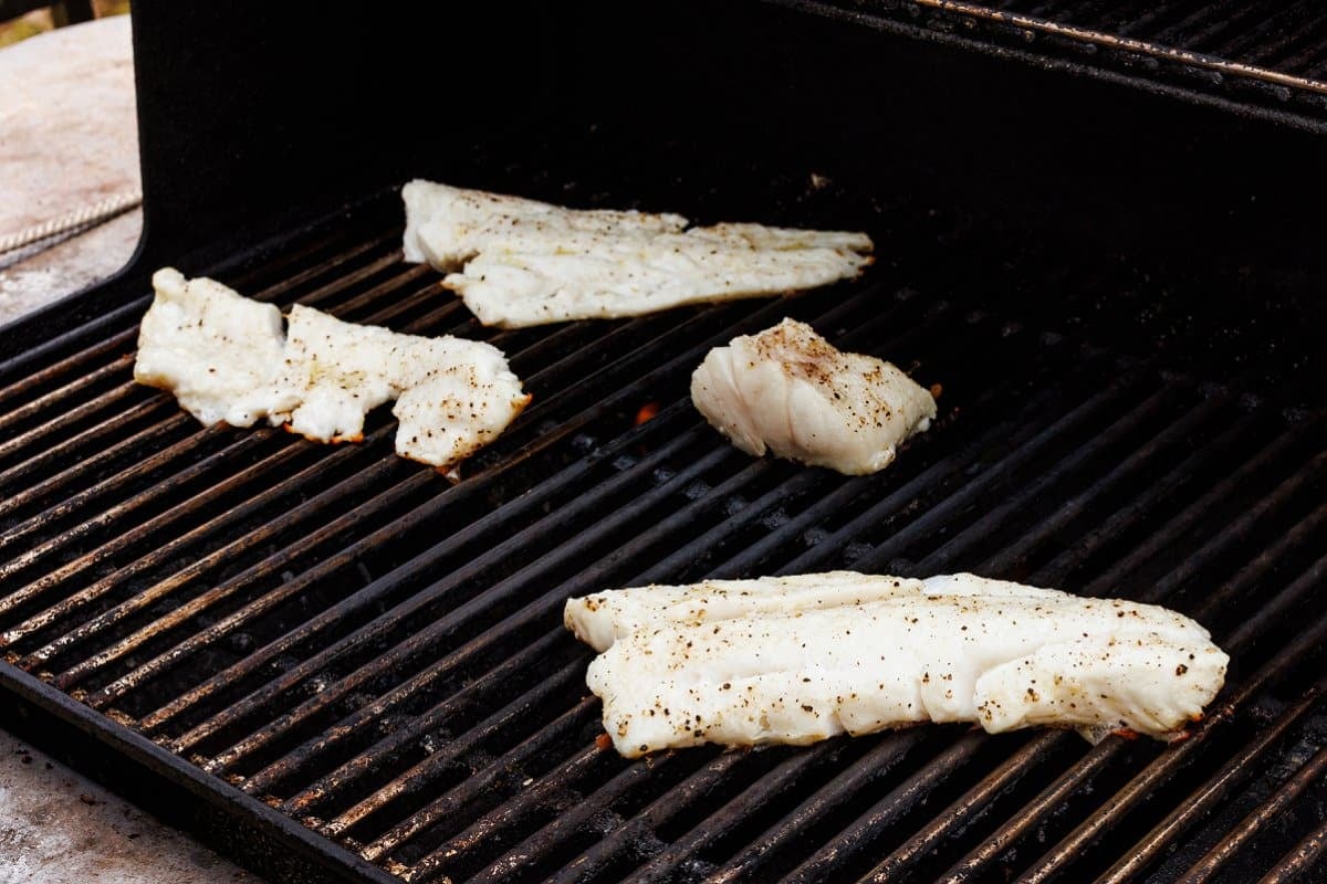 Cooking white fish on the grill outside.