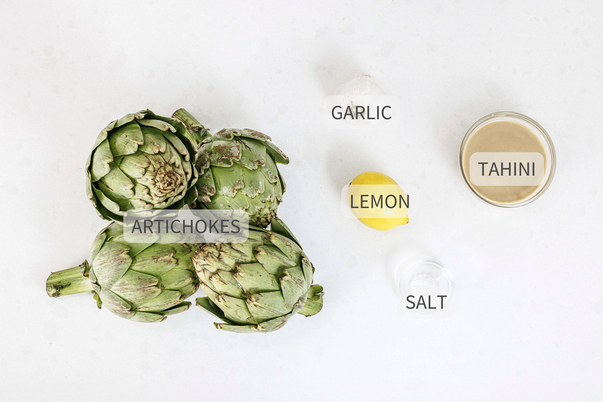Labeled ingredients for steamed artichokes with tahini.