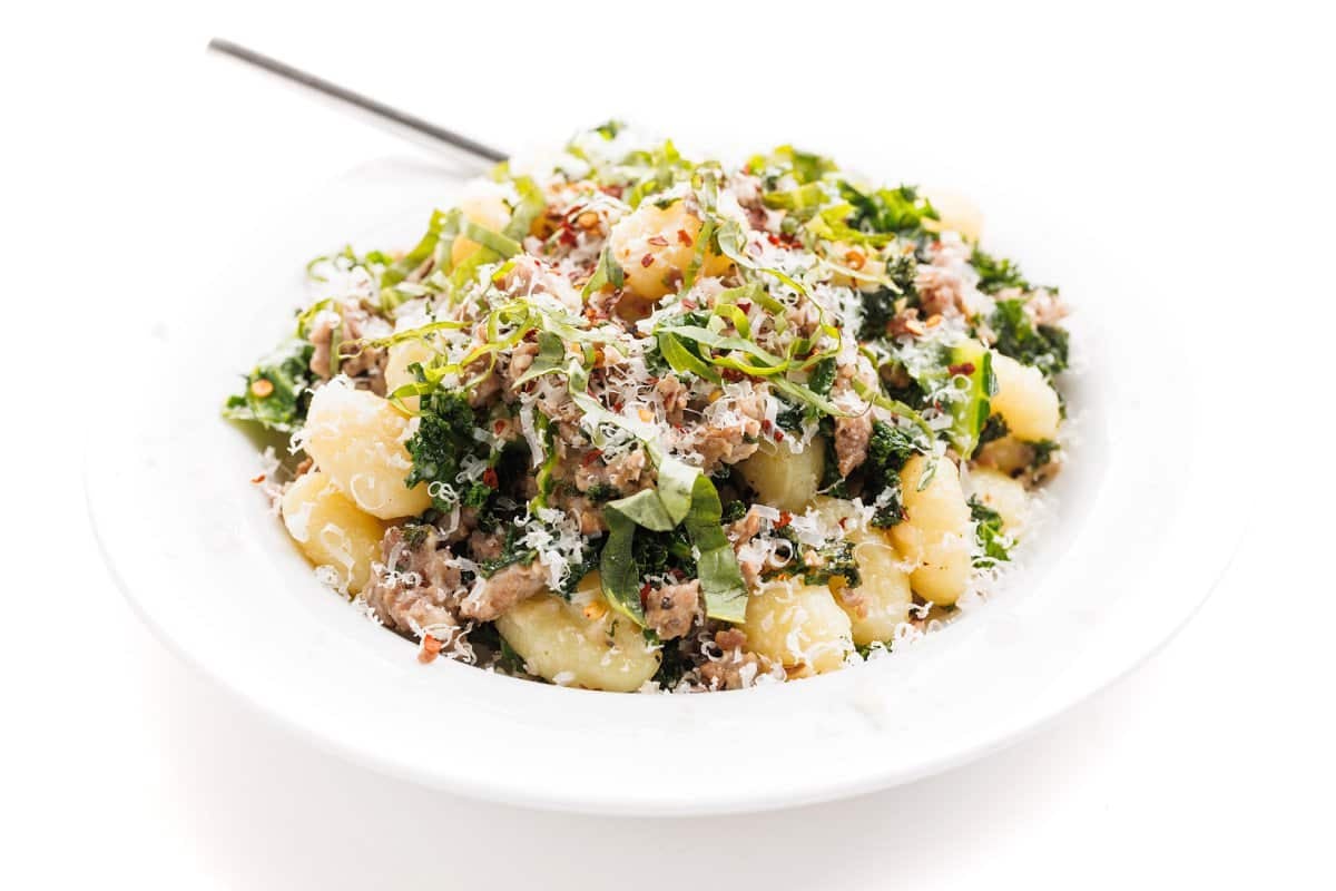 Wide bowl of sausage and kale gnocchi pasta.