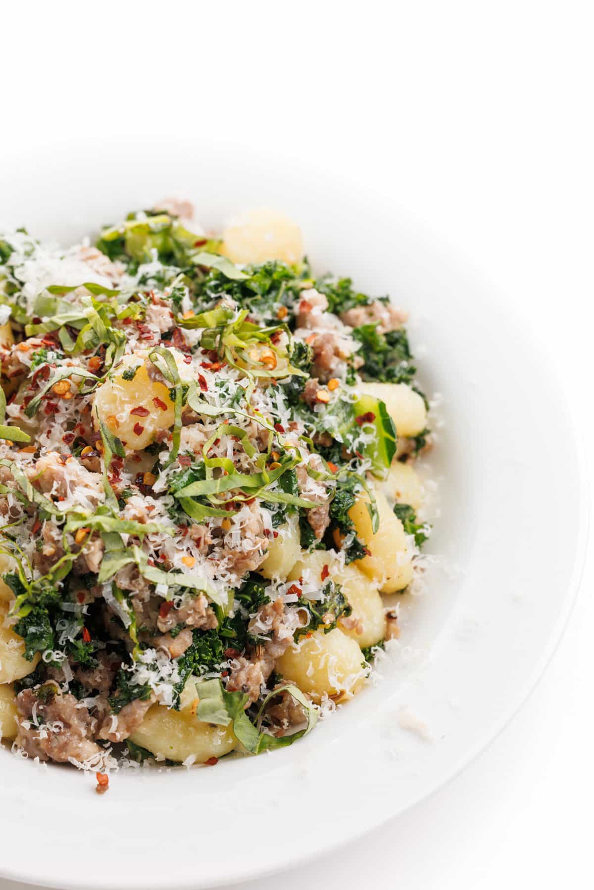 Sausage and kale gnocchi topped with shredded parmesan and fresh herbs.