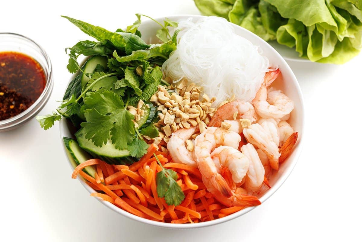 Vietnamese shrimp noodle bowl with fresh herbs, peanuts, and carrots.