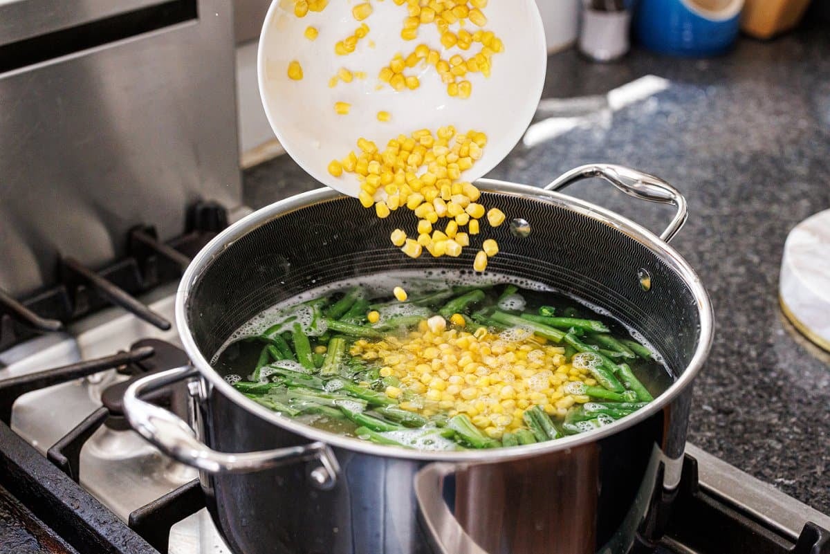 Adding corn kernels to pot of water.