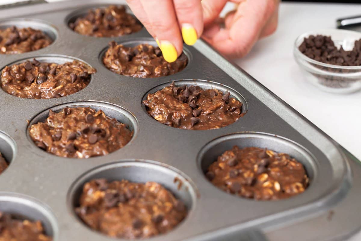 Muffin tin filled with chocolate muffin batter.