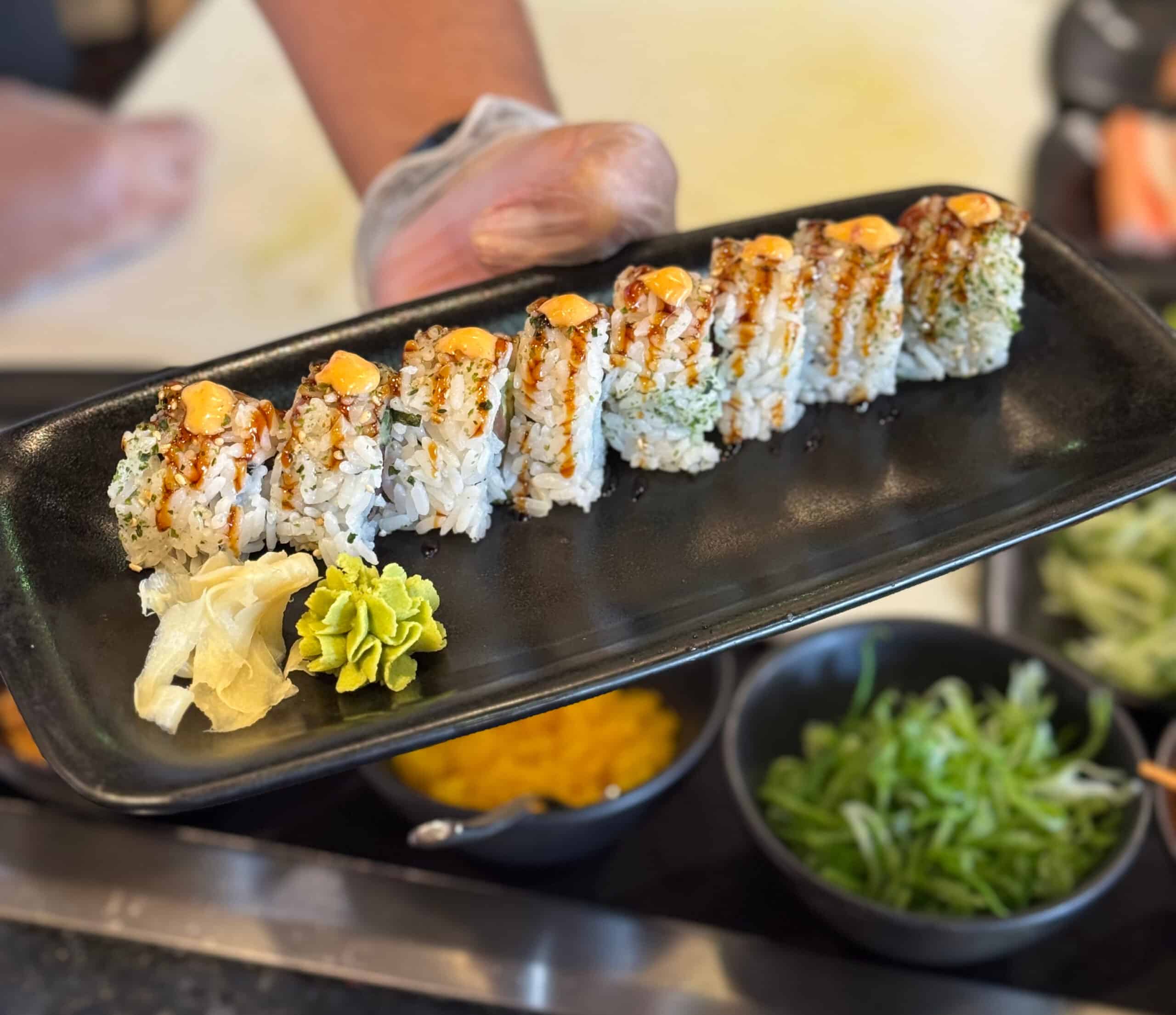 Sushi roll on a plate with ginger and wasabi.