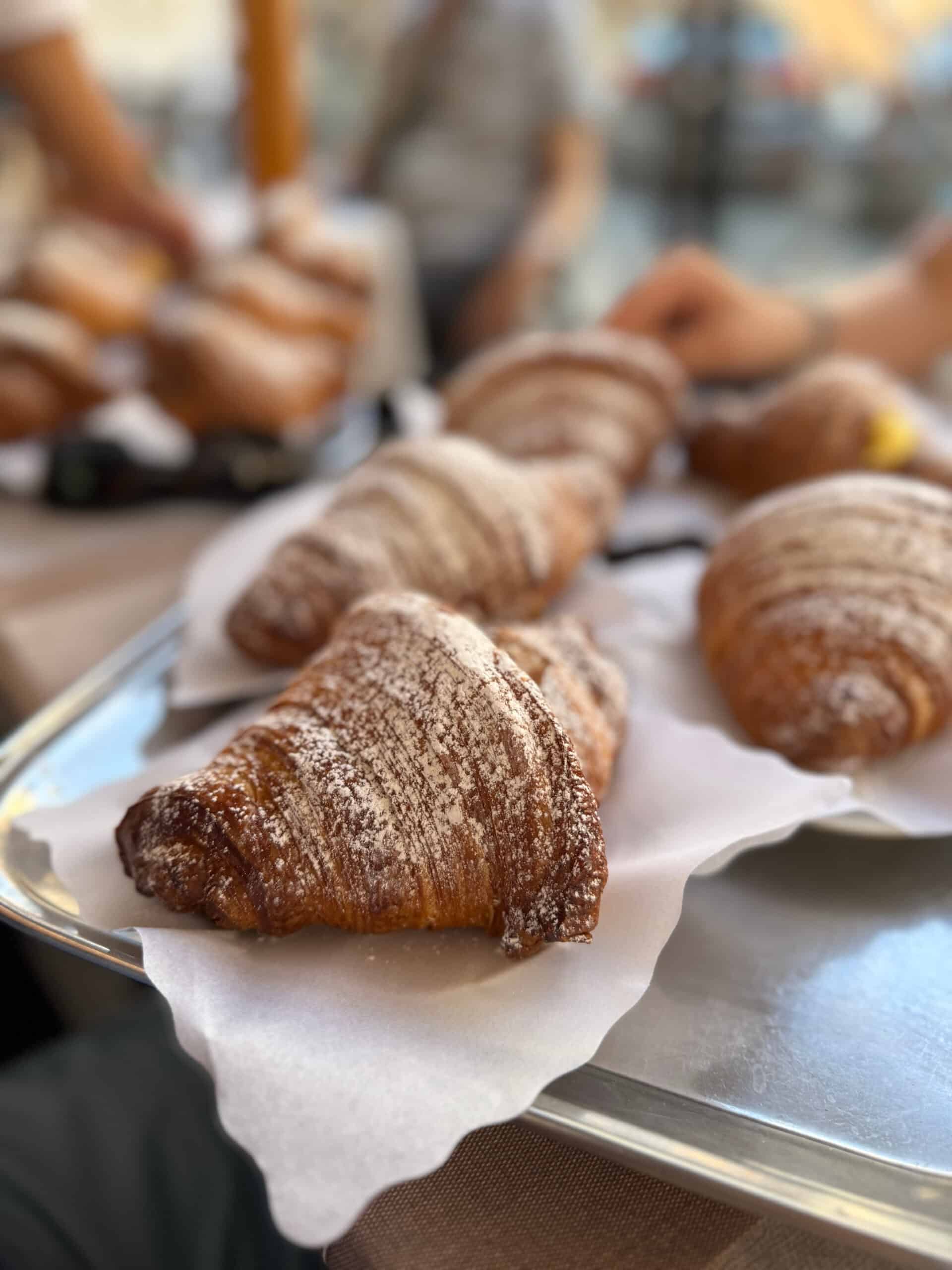 Cornettos sprinkled with powdered sugar on a serving tray.