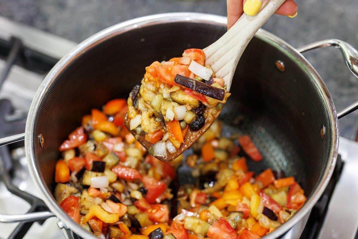 Eggplant caponata cooking in a large saucepan.