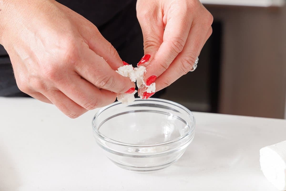 Crumbling goat cheese into a small bowl.
