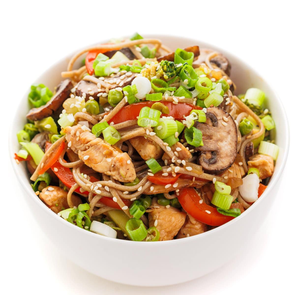 Spicy chicken and soba noodles in a bowl topped with green onion and sesame seeds.