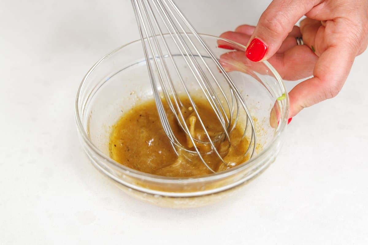 Whisking lime vinaigrette in a small glass bowl.