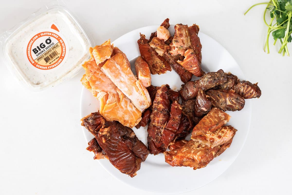 Smoked salmon jerky on a plate next to a container of smoked whitefish dip.