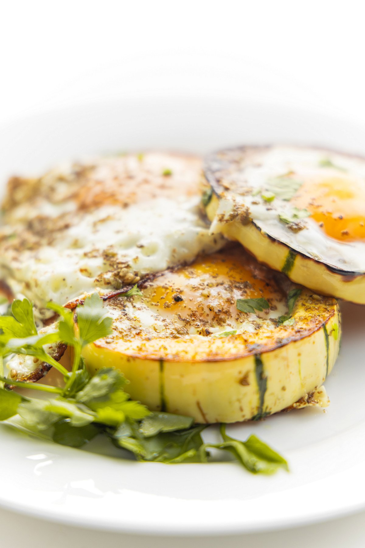 Delicata squash egg cups with za'atar on a plate with fresh parsley.